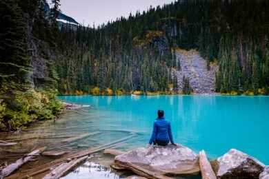 woman sitting in front of light blue lake