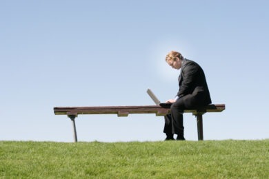 man sitting on bench working on laptop