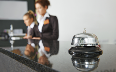 A hotel front desk with a silver bell
