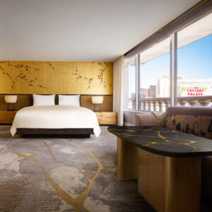 A hotel room in Nobu Hotel Caesars Palace with a yellow accent wall, large glass sliding doors and grey carpet