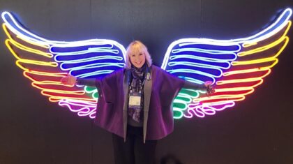 Smart Meetings CEO Marin Bright posing in front of neon wings