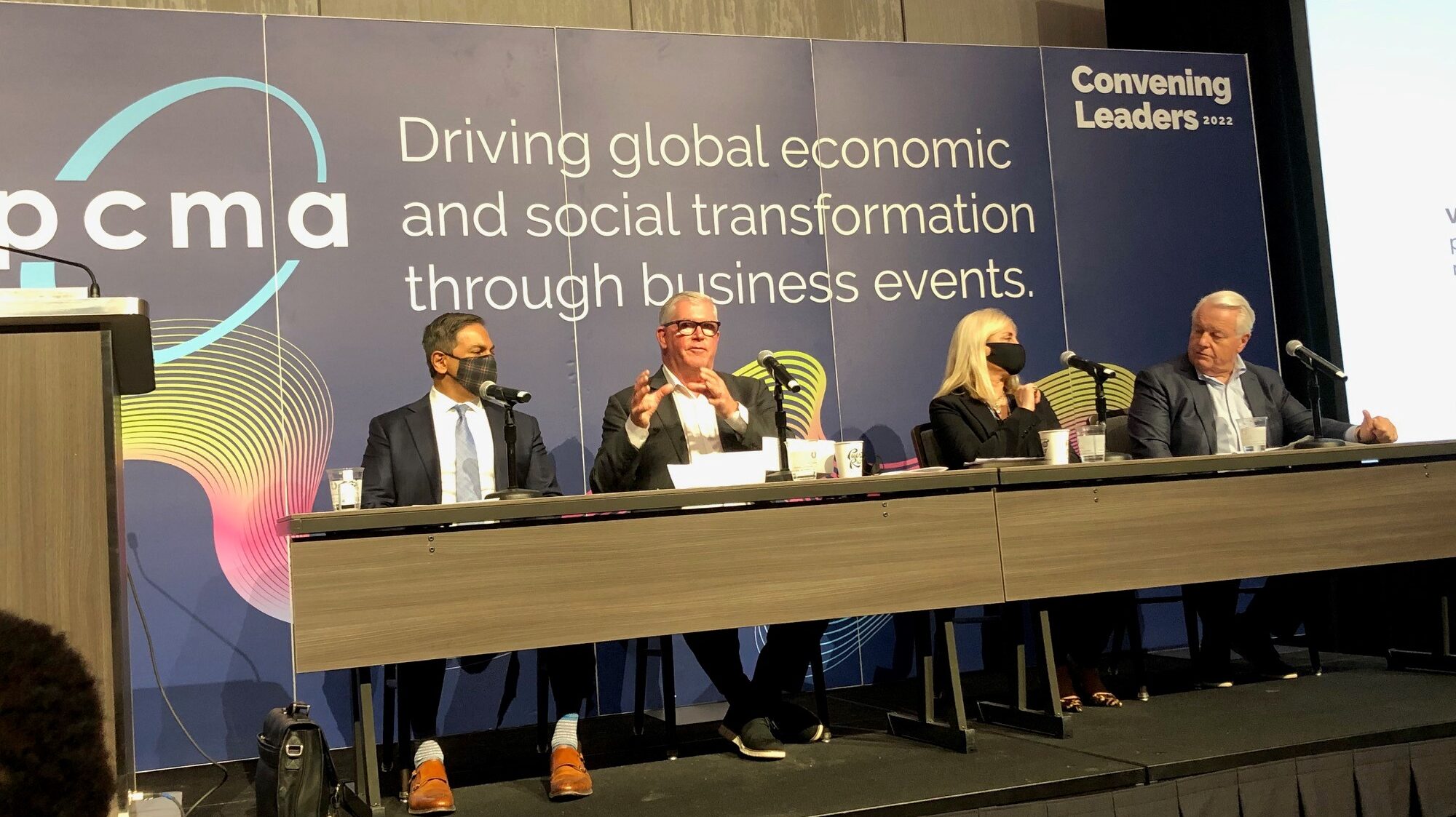 A panel of people speaking at PCMA. The board behind them reads, "Driving global economic and social transformation through business events."