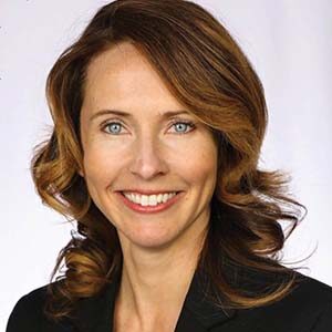 A portrait of Amanda Armstrong. She is a white woman with highlighted wavy hair and a black suit jacket
