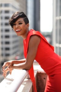 A portrait of Jade Simmons. She is leaning over a ledge with a red dress
