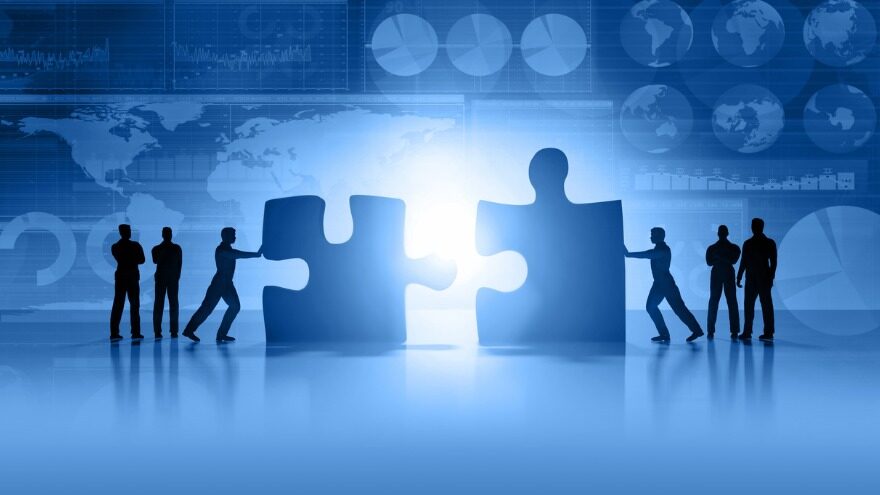 Two group of people pushing large puzzle pieces together