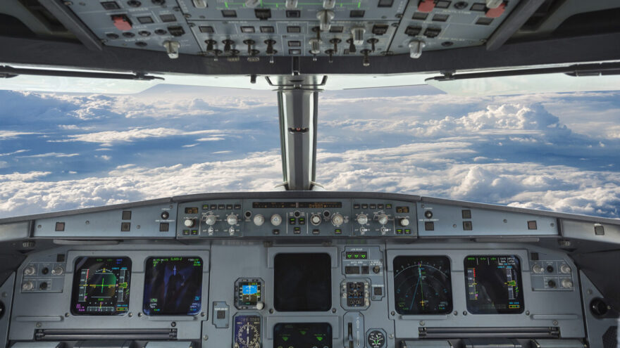 The interior of a plane's cockpit looking over rolling hills