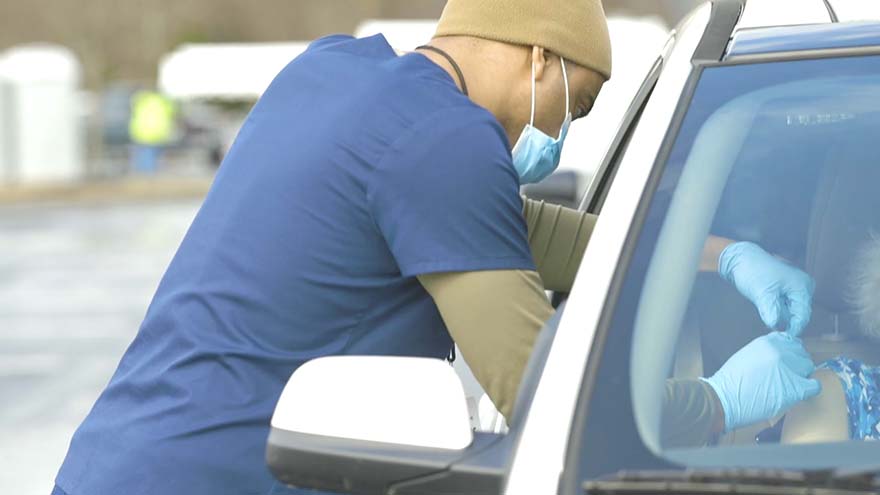 A nurse performing a Covid test through a car window