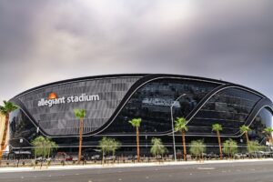 The exterior of Allegiant Stadium in Las Vegas. It is black and surrounded by palm trees