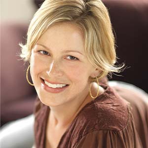 A portrait of Kate Brack. She is a blonde white woman with short hair and a dark red blouse.