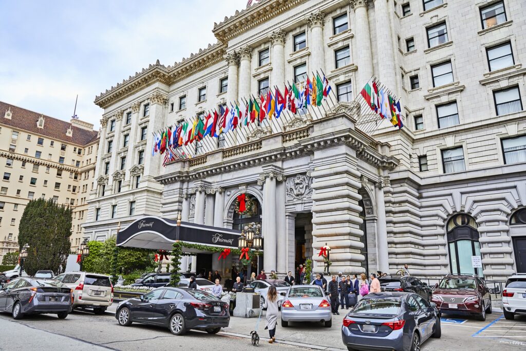 The front of Fairmont San Francisco. The Neoclassical arch over the entryway has many national flags