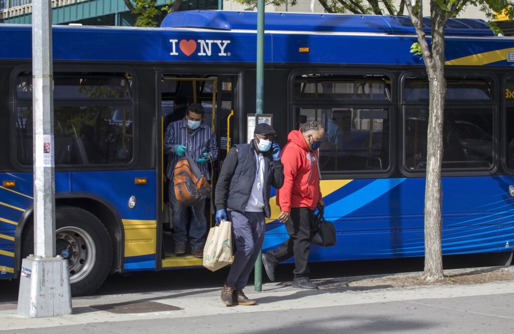 Several men stepping off a blue bus in the Bronx, New York