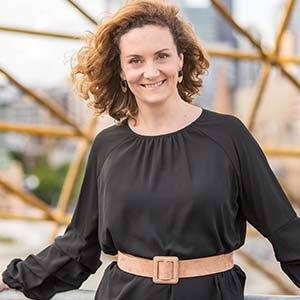 A portrait of Claire Spencer. She is a white woman with curly brown hair and a black dress