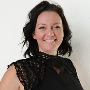 A portrait of Gemma Fortier. She is a white woman with short wavy black hair and a lacy black blouse