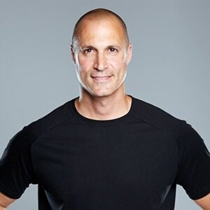 A portrait of Nigel Barker. He is a bald white man with a black shirt.