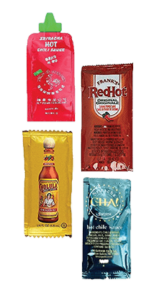 Four miniature packets of various hot sauces like Sriracha, Cholula and Frank's redhot