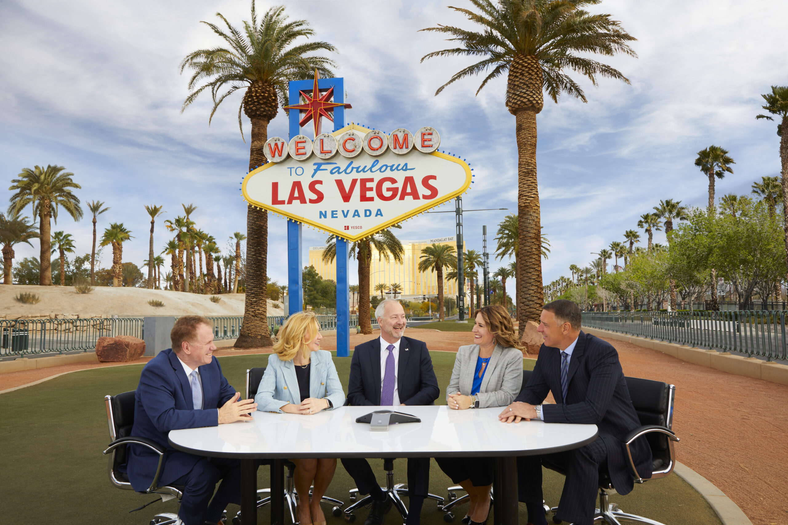 A series of executives sitting in front of the "Welcome to Fabulous Las Vegas" sign.