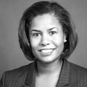 A black and white portrait of meetings professional Julie Coker. She is a black woman with short strait hair and a striped suit jacket