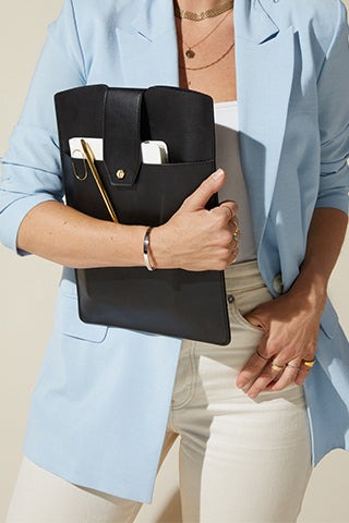 A woman holding a black faux leather organizer with a gold pen