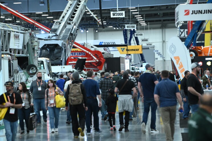 The west hall exhibits at the World of Concrete convention. Various machinery is on display to a crowd.