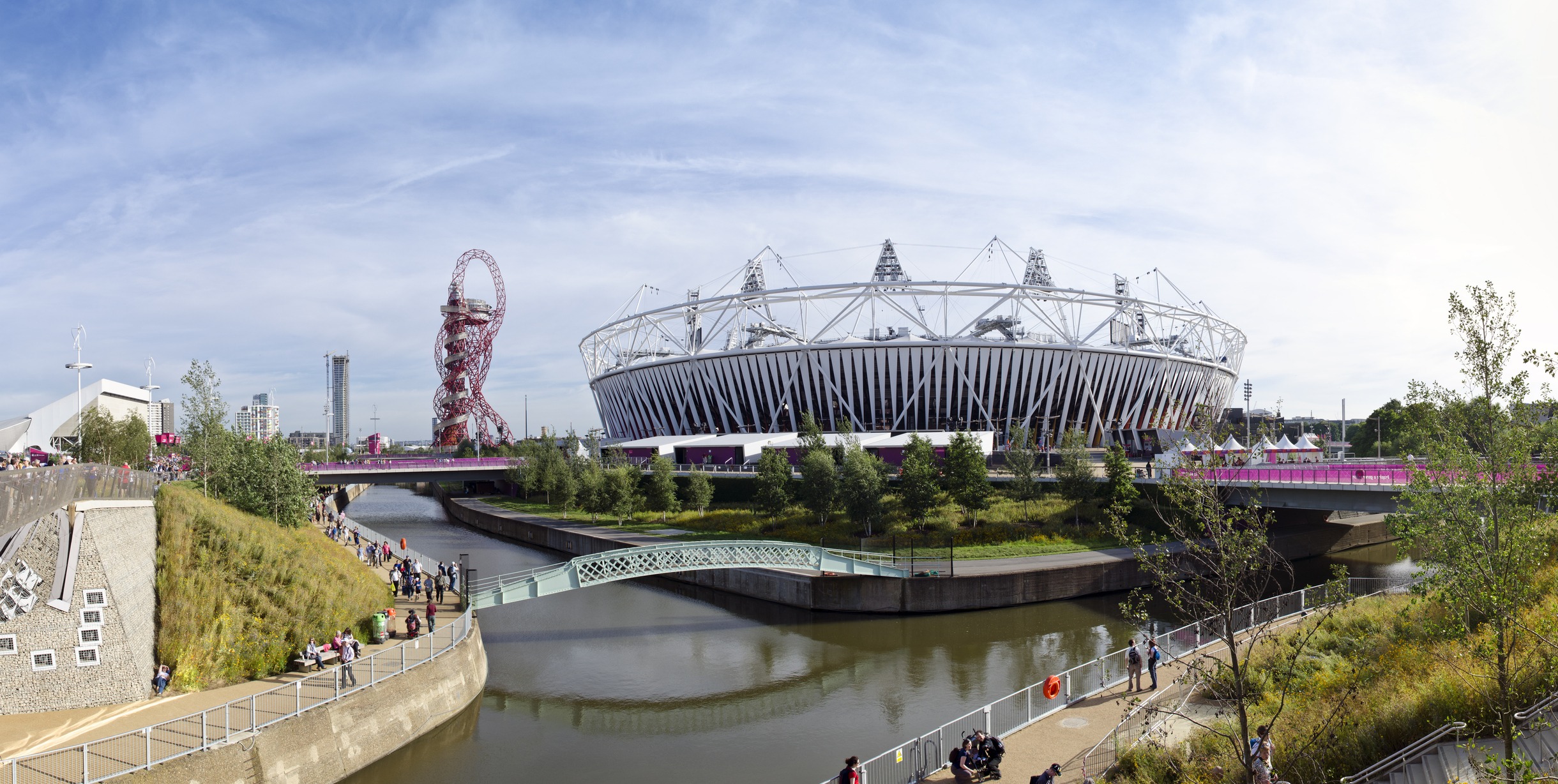 The Queen Elizabeth Olympic Park and The Slide at the ArcelorMittal Orbit, London. A stadium sits next to a river with two bridges leading to it.