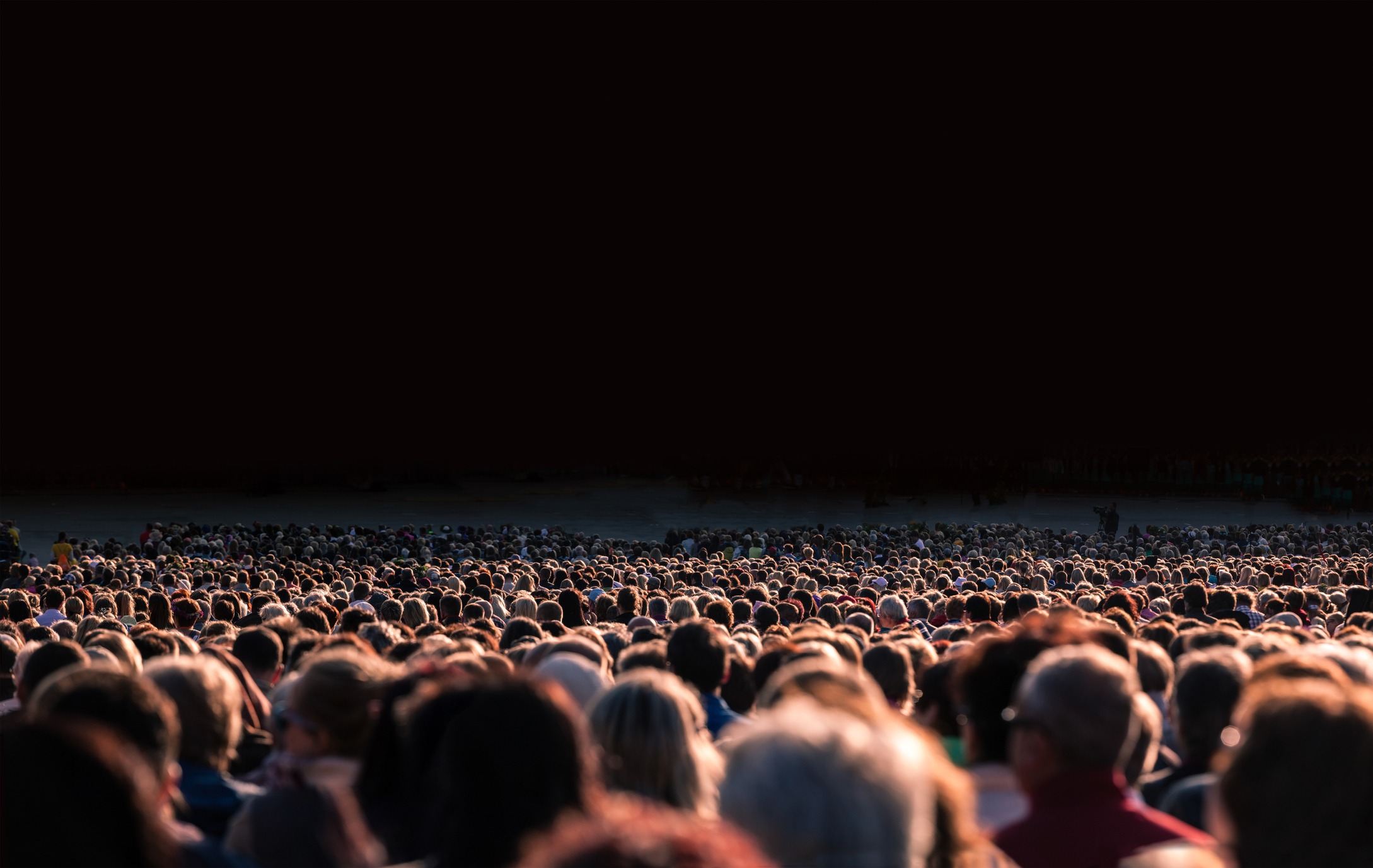 A large crowd of people under a dark gradient.