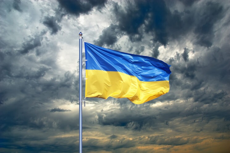 A Ukraine flag waves in front of a dark cloudy sky.