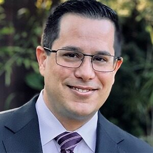 A portrait of Alex Batista, the new vice president of convention sales at Greater Miami Convention & Visitors Bureau. He is a white man with dark hair and square glasses.