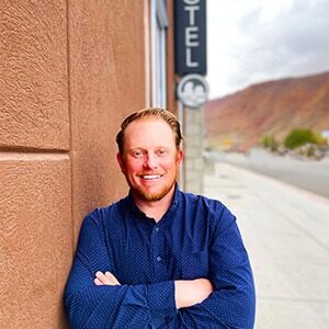 A portrait of Colton Call, new general manager of Radcliffe Moab in Utah. He is a white, red-haired man with a blue collared shirt.