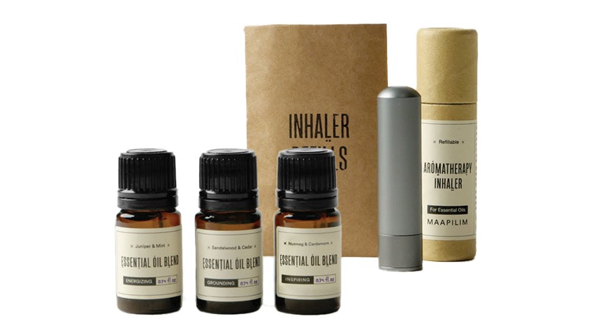 A small grey essential oil diffuser with three small bottles of essential oil blends