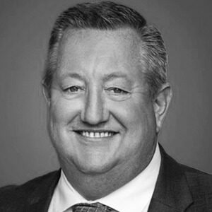 A black and white portrait of Paul Jansen. He is a white man with short combed hair and a black suit.