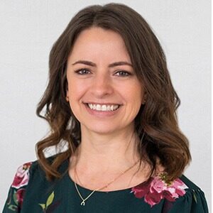 A portrait of Michelle Haider, the new director of event experience for Visit Milwaukee. She is a white woman with loosely curled brown hair and a floral blouse.