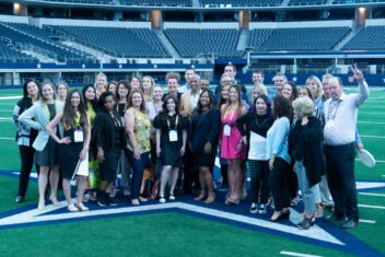 The attendees of the Smart Meetings one-day Regional Experience pose together on a football field.