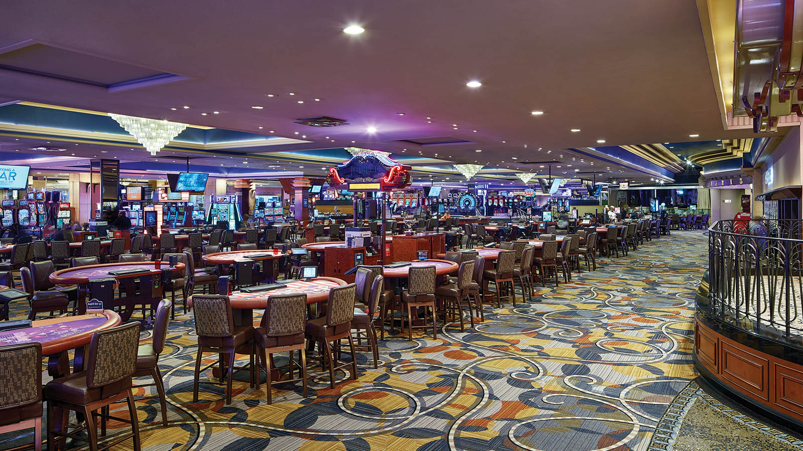 The Paris Casino in Harrah's Las Vegas. A long row of various gambling tables are in front of electronic gaming machines.