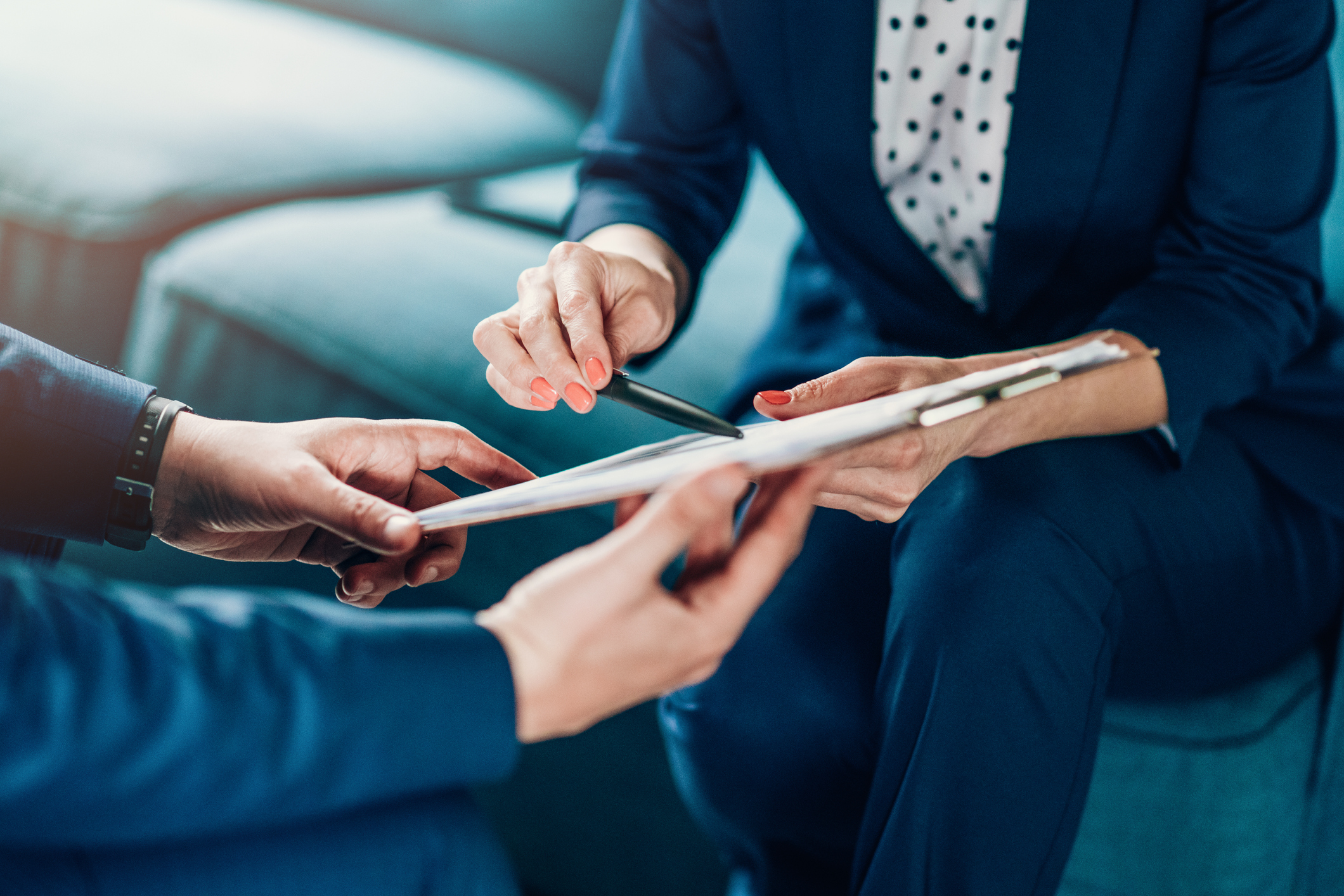 Two people holding a clipboard. One is holding a pen to sign a contract.