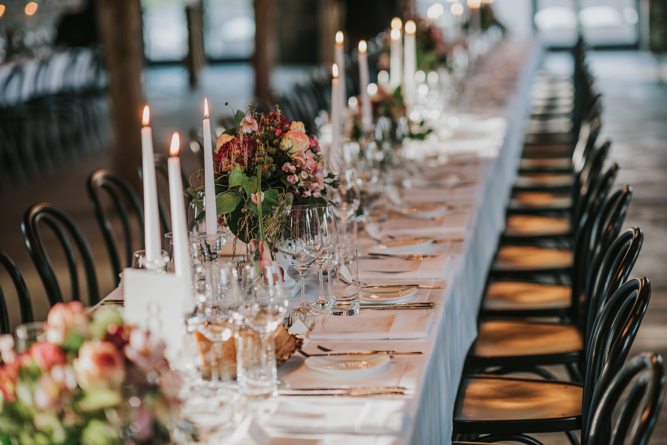 A long banquet table with tall candles and vases of flowers along the center.