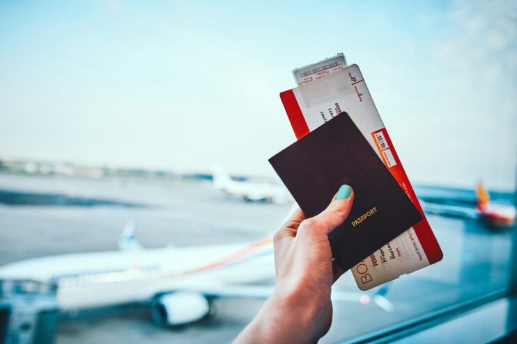 A stock image of a person holding a passport and boarding pass.