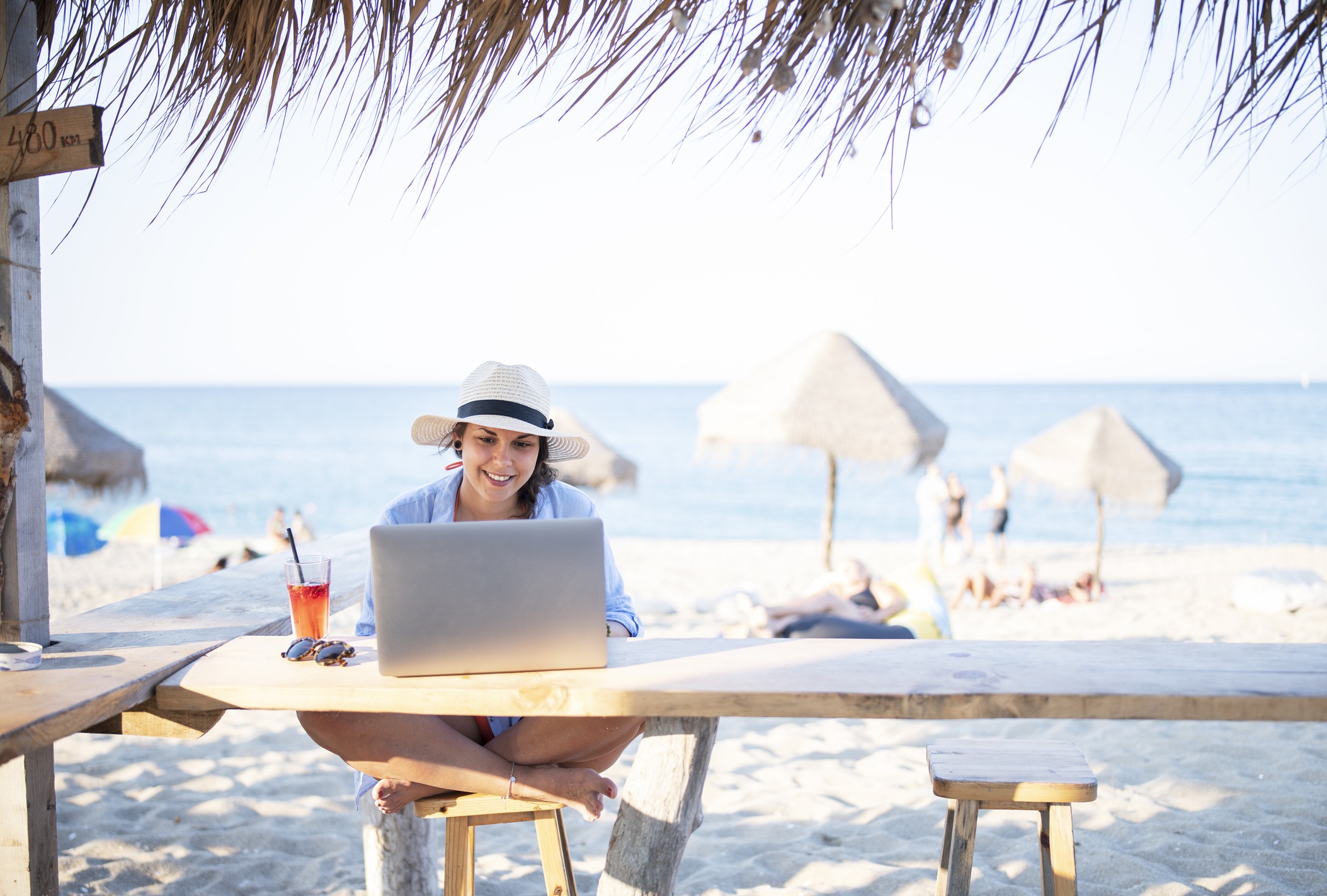 A woman working on a laptop on the beach.