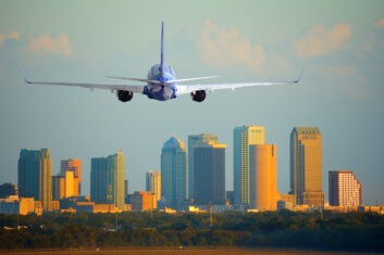 A plane descends with the Tampa skyline in the background.