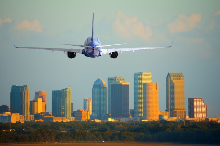 A plane descends with the Tampa skyline in the background.