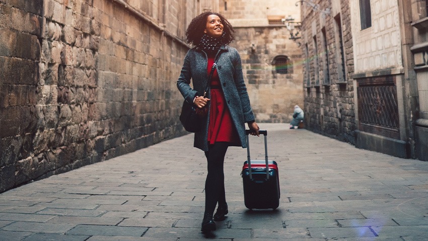 A black woman pulling her suitcase participating in tourism