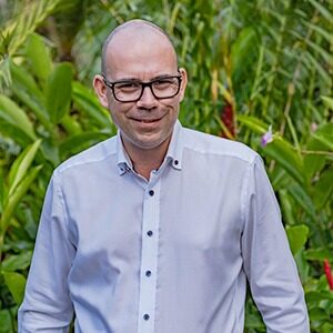 A portrait of Marcel Stittner. He is a white man with square glasses wearing a white collared shirt.