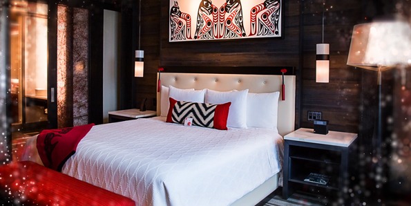 A hotel bed in Tulalip Resort and Casino. It features Native American artwork above the headboard.