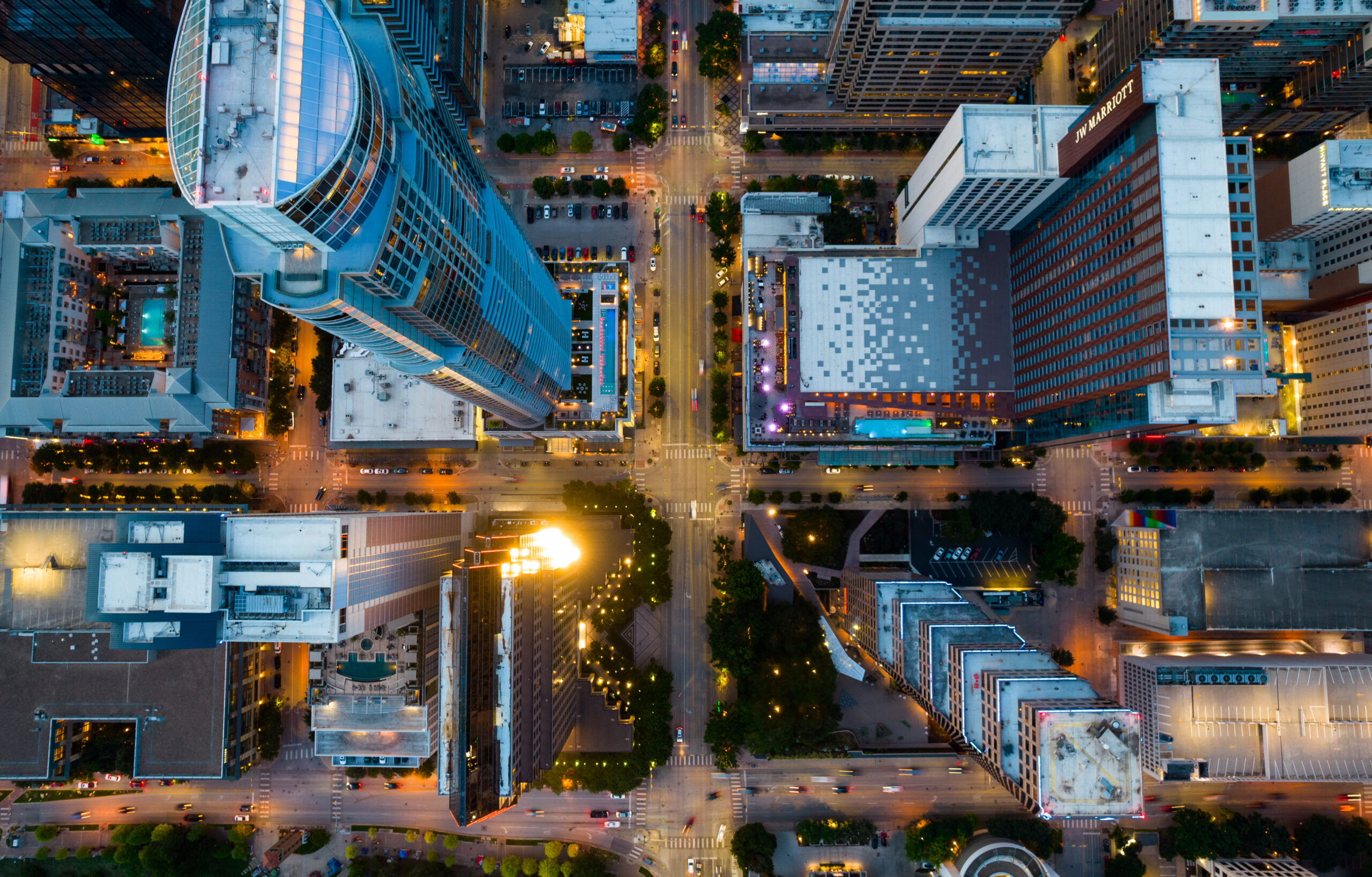 An aerial shot of a city intersection, facing straight down above several skyscrapers. 