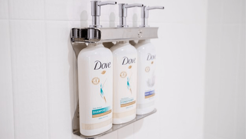 Large bottles of Dove toiletries attached to a shower wall.