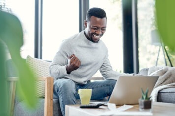 A stock image of a laughing man working on a laptop.