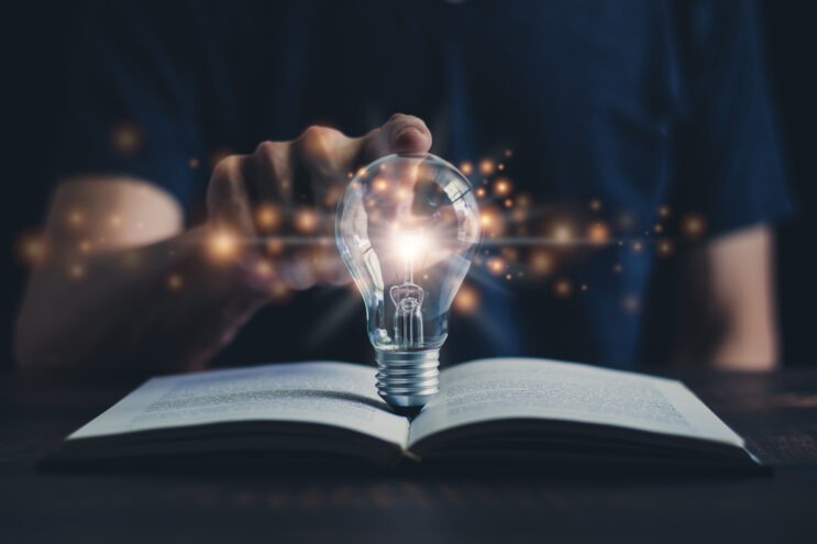 A stock image of a glowing lightbulb on top of an open book.