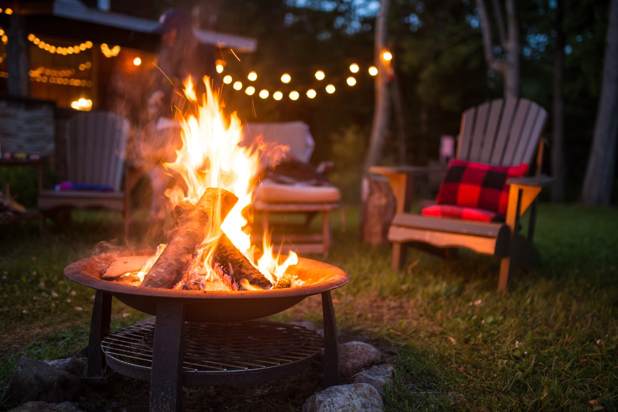 Camp Lincoln in Hubert, Minnesota. Wooden lounge chairs circle a fire pit in the late evening. Retreats like this are more down to earth.