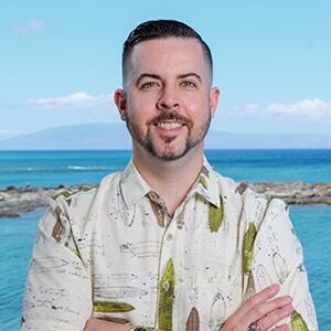 A portrait of Nicholas Kuhns. He is a white man with combed black hair, a short beard and a Hawaiian shirt.