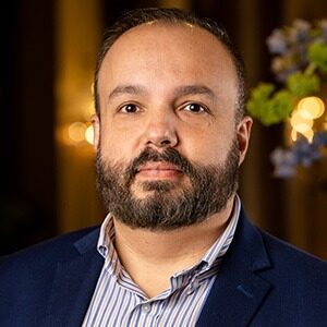 A portrait of Randall Scott-Miller. He is a brown man with a black beard and blue suit.