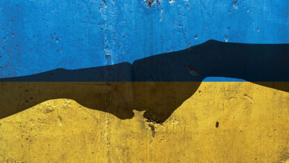A silhouette of two hands fist bumping over the Ukraine flag.